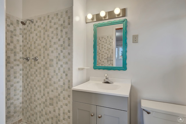 bathroom with vanity, toilet, and a tile shower