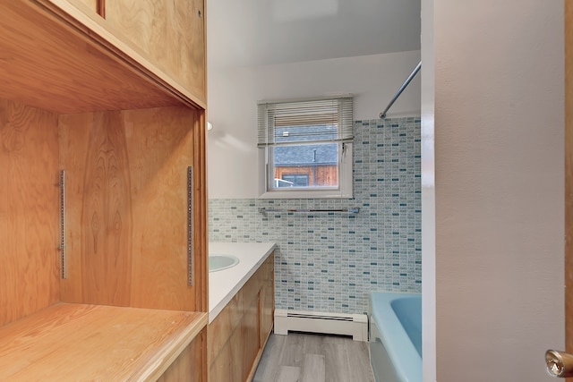 bathroom with vanity, tile walls, a baseboard radiator, and tub / shower combination