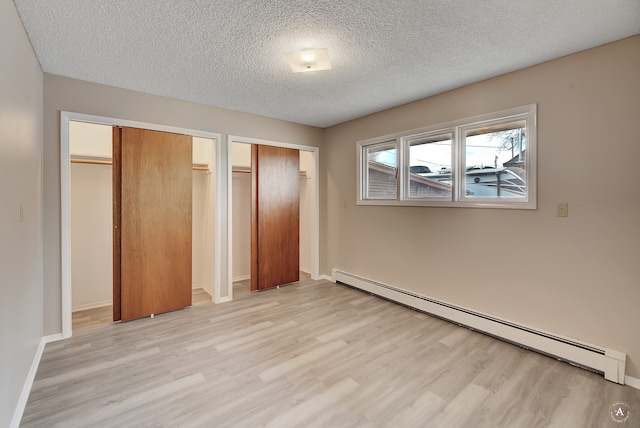 unfurnished bedroom with baseboard heating, a textured ceiling, and light hardwood / wood-style floors