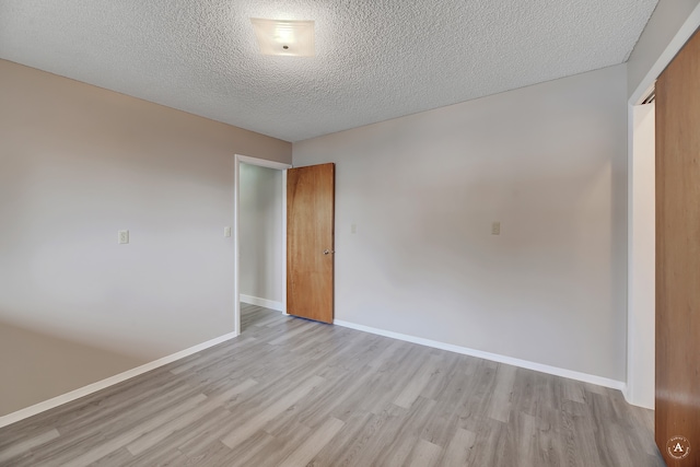 unfurnished room with light hardwood / wood-style flooring and a textured ceiling