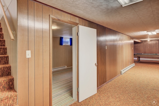 hallway featuring light colored carpet, a baseboard radiator, and wooden walls