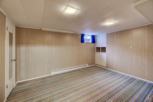 carpeted empty room with a baseboard heating unit and wooden walls