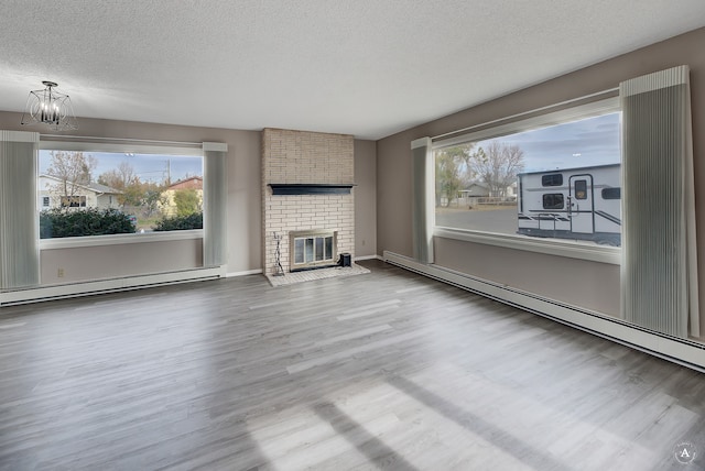 unfurnished living room with a textured ceiling, wood-type flooring, a baseboard radiator, and a fireplace