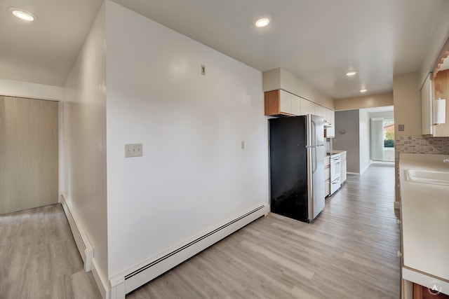 kitchen featuring a baseboard heating unit, white range with electric cooktop, light hardwood / wood-style floors, and stainless steel refrigerator