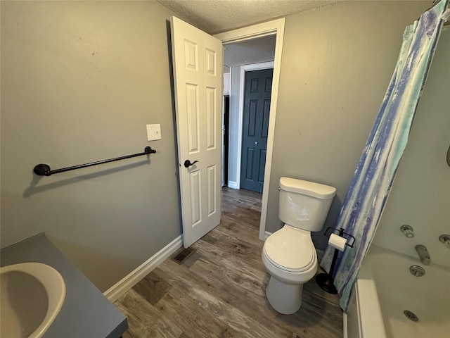 full bathroom with vanity, a textured ceiling, hardwood / wood-style floors, toilet, and shower / bath combo with shower curtain