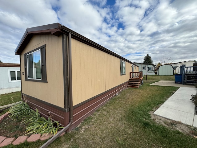 view of side of property with a yard, a storage unit, and a wooden deck