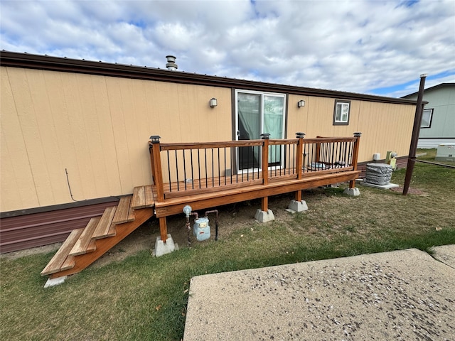 rear view of house featuring a wooden deck and a lawn