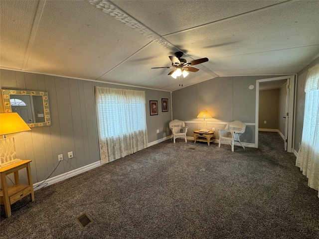 unfurnished room featuring ceiling fan, vaulted ceiling, dark carpet, and a textured ceiling