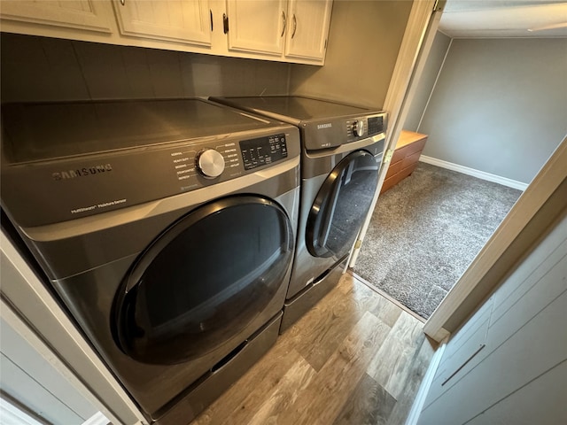 laundry area with cabinets, separate washer and dryer, and light hardwood / wood-style flooring