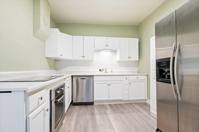 kitchen featuring stainless steel appliances, light hardwood / wood-style floors, sink, tasteful backsplash, and white cabinets