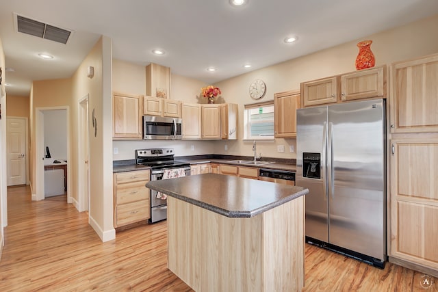 kitchen featuring light brown cabinets, stainless steel appliances, a center island, and light hardwood / wood-style flooring