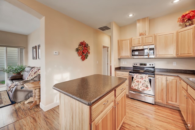 kitchen with light brown cabinetry, appliances with stainless steel finishes, light hardwood / wood-style floors, and a center island