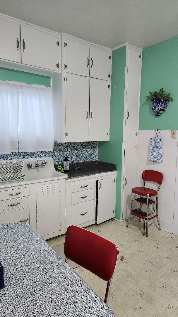 kitchen with tasteful backsplash, white cabinetry, and white refrigerator