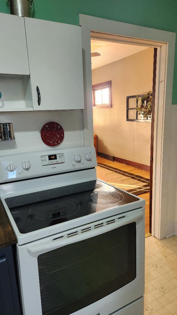 kitchen featuring white cabinetry and white electric stove