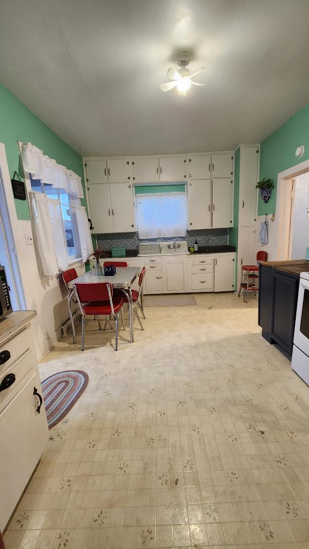 kitchen with tasteful backsplash, white range with electric stovetop, white cabinetry, and ceiling fan