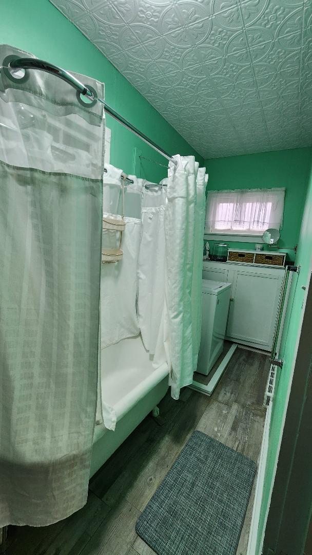 bathroom with independent washer and dryer, hardwood / wood-style flooring, and shower / bath combination with curtain