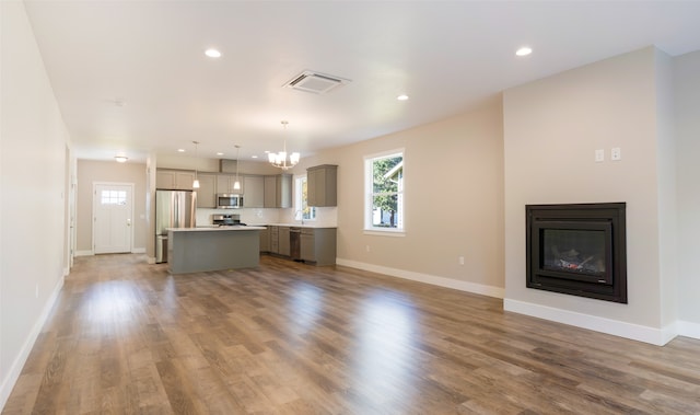 unfurnished living room featuring a chandelier, wood-type flooring, and sink