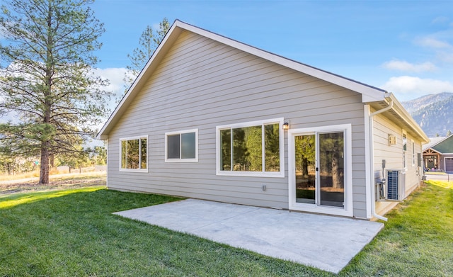 back of house with a mountain view, a yard, central AC, and a patio area