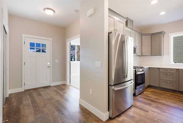 kitchen with dark hardwood / wood-style floors, gray cabinets, backsplash, and appliances with stainless steel finishes