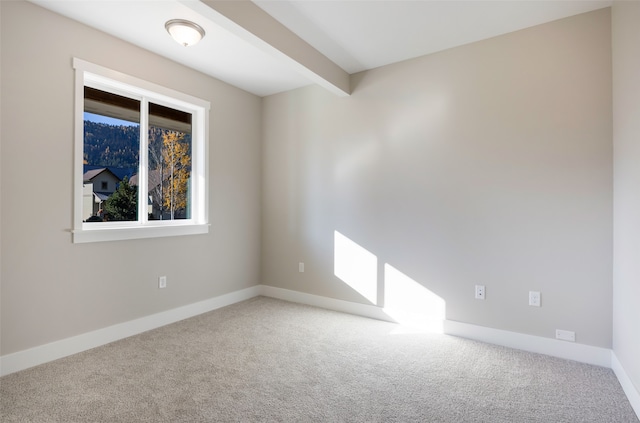 carpeted spare room with beamed ceiling