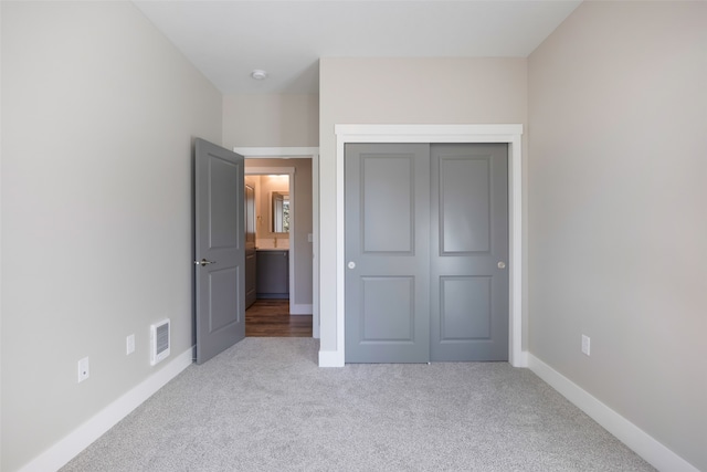 unfurnished bedroom with light carpet and a closet