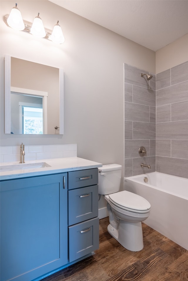 full bathroom featuring hardwood / wood-style floors, vanity, toilet, and tiled shower / bath