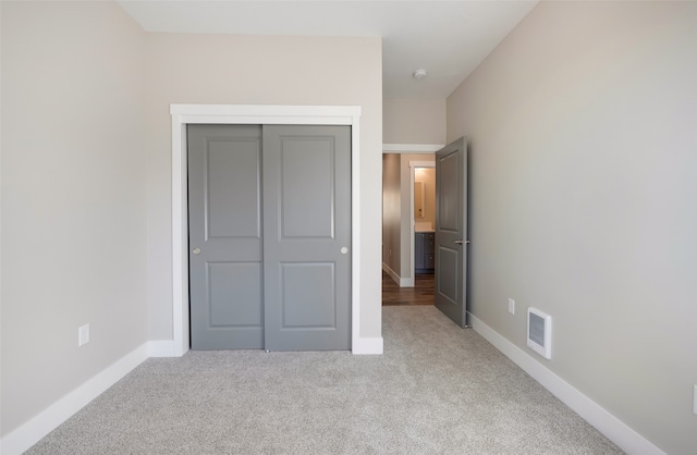 unfurnished bedroom with light carpet and a closet