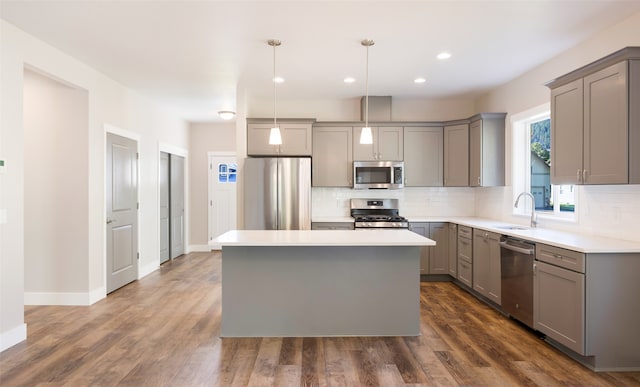 kitchen featuring gray cabinetry, sink, stainless steel appliances, pendant lighting, and a kitchen island