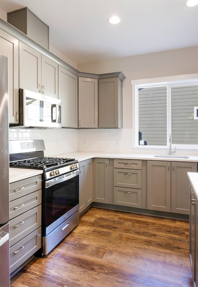 kitchen with dark hardwood / wood-style flooring, tasteful backsplash, gray cabinetry, gas range, and sink