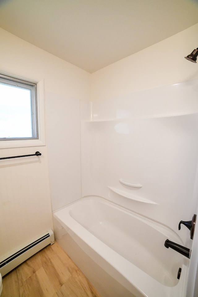 bathroom featuring wood-type flooring, shower / washtub combination, and a baseboard heating unit