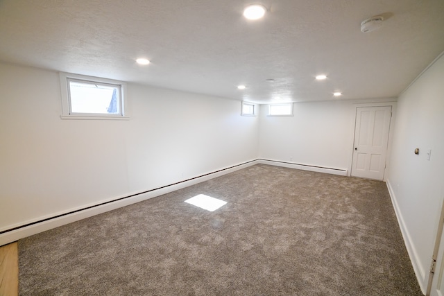 basement with carpet, a textured ceiling, and baseboard heating