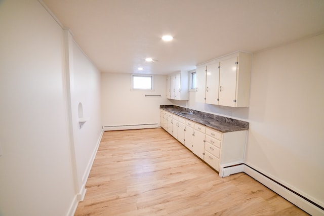 kitchen with light hardwood / wood-style floors, a baseboard radiator, sink, and white cabinetry