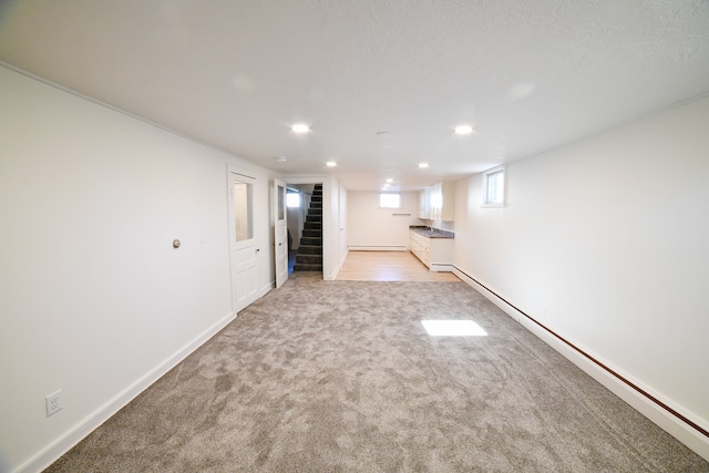 basement featuring light carpet and a baseboard heating unit