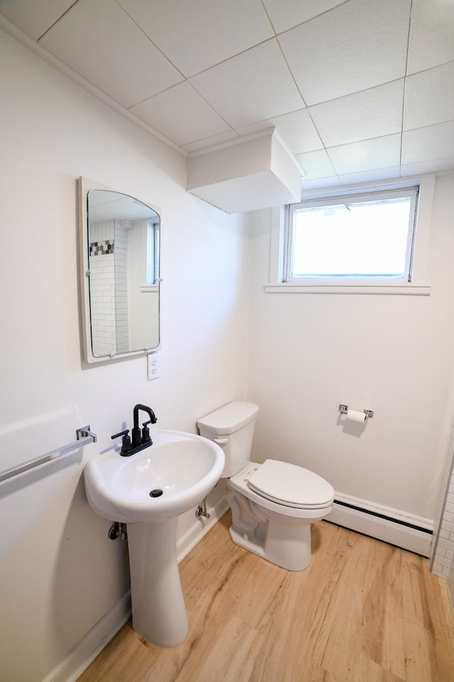 bathroom with hardwood / wood-style floors, a baseboard radiator, and toilet