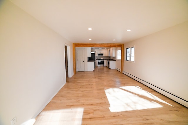 unfurnished living room with a baseboard radiator, light hardwood / wood-style flooring, and sink