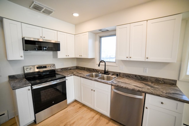 kitchen featuring a baseboard radiator, sink, white cabinetry, light wood-type flooring, and appliances with stainless steel finishes