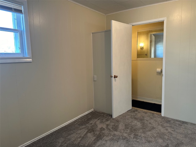 unfurnished bedroom with wooden walls and dark colored carpet