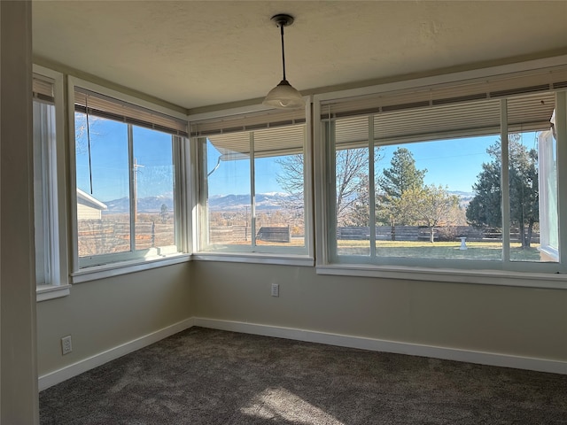 unfurnished sunroom featuring a mountain view and a healthy amount of sunlight