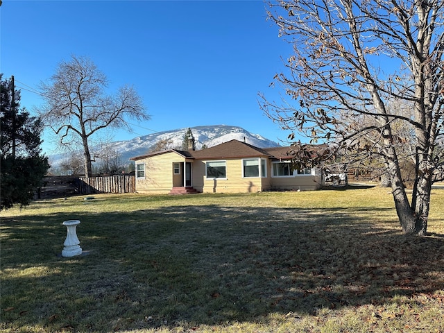 back of property with a mountain view and a lawn