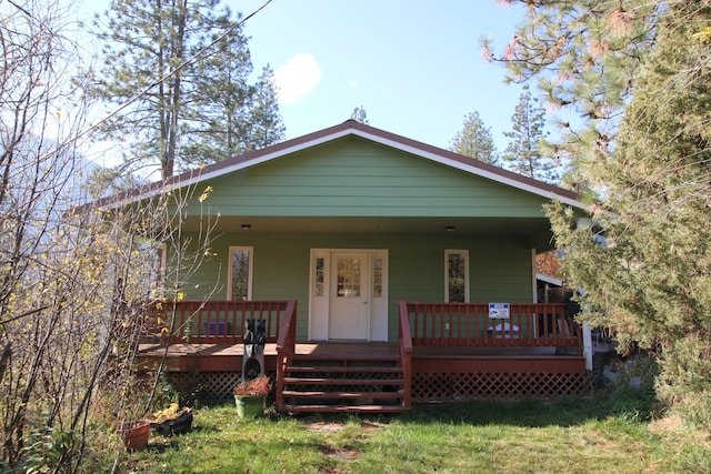 rear view of property featuring a lawn and a wooden deck