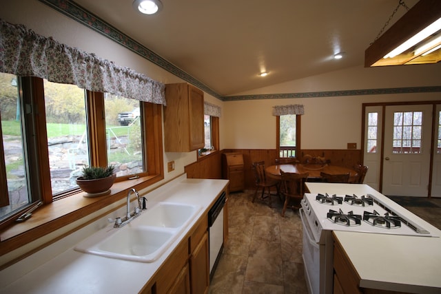 kitchen with wood walls, sink, white range with gas stovetop, lofted ceiling, and dishwasher