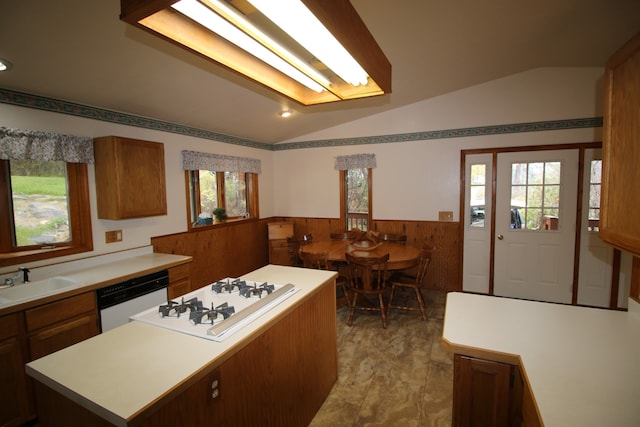 kitchen featuring lofted ceiling, a center island, wood walls, sink, and white appliances