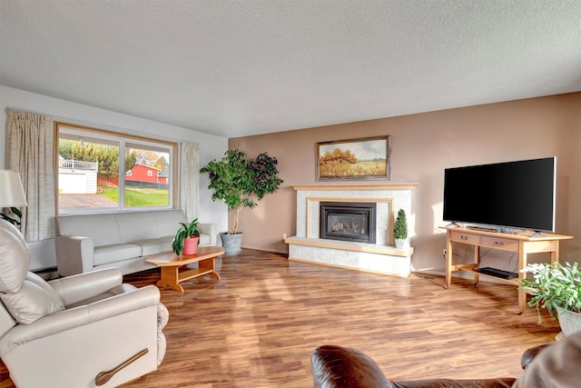 living room featuring a tile fireplace, light hardwood / wood-style flooring, and a textured ceiling