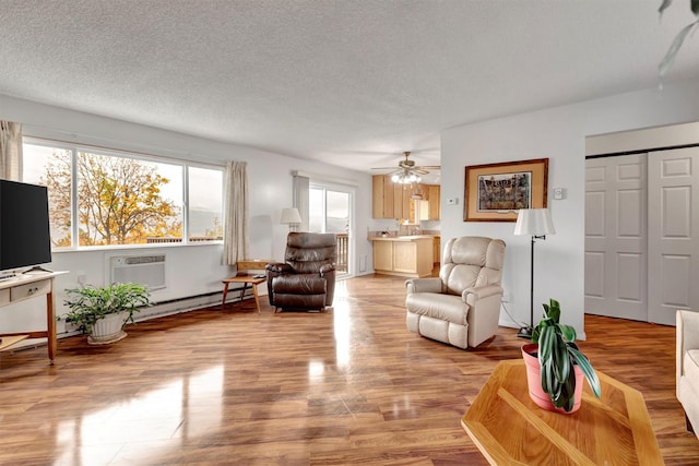 living room with baseboard heating, a wall mounted air conditioner, a textured ceiling, ceiling fan, and light wood finished floors