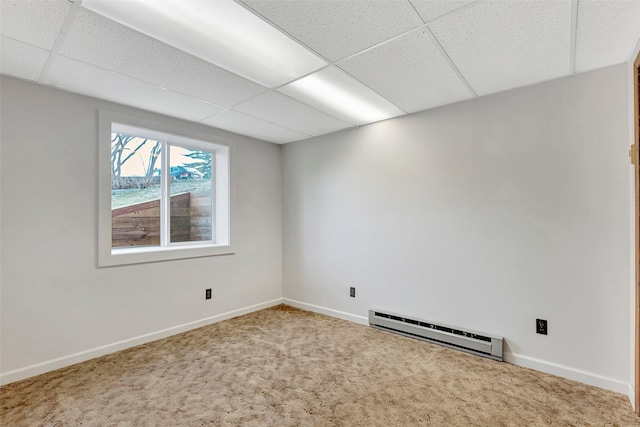 carpeted empty room featuring a drop ceiling, baseboards, and baseboard heating