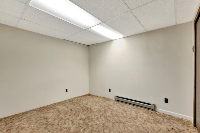 carpeted empty room featuring a drop ceiling and a baseboard radiator