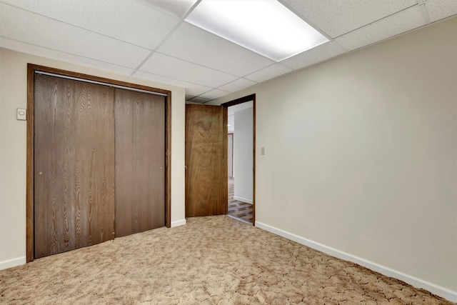 unfurnished bedroom with a paneled ceiling, carpet floors, and a closet