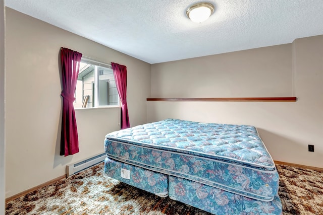 carpeted bedroom featuring a baseboard heating unit and a textured ceiling