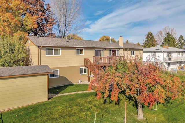 back of property featuring a chimney, stairs, a wooden deck, an outbuilding, and a yard