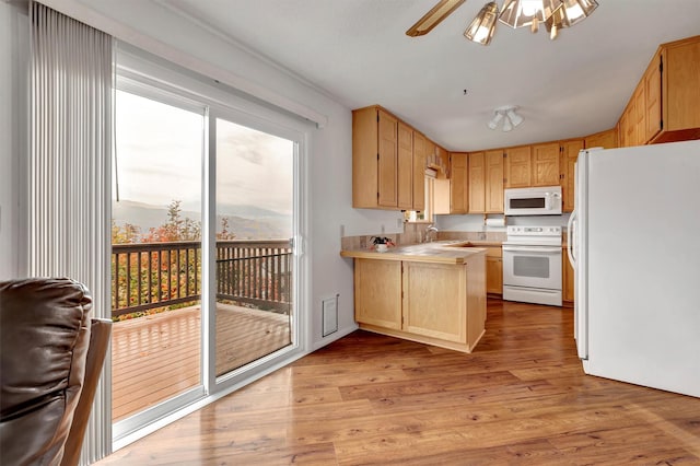 kitchen with white appliances, light wood-style flooring, light countertops, a ceiling fan, and a peninsula